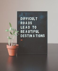 a sign that reads difficult roads lead to beautiful destinations with a plant next to it