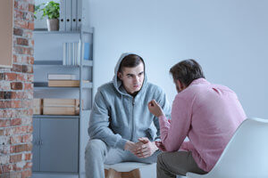 a teen boy talks to a counselor during his meth addiction treatment program