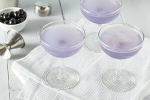 Three cocktail glasses filled with a purple liquid represent purple drank