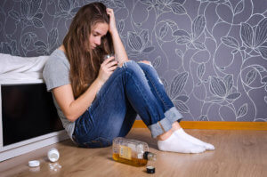 a woman sitting in the corner thinking about substance use disorder treatment