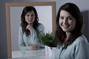 teen stares at her fake smiling self in anger to represent the need for a teenage mood disorder treatment program